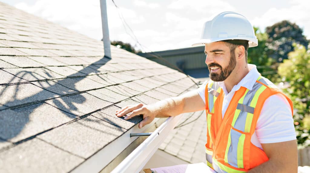how to file a roof insurance claim roofing specialist or insurance adjuster in orange safety vest and white hard hat performing a professional roof inspection on asphalt roof