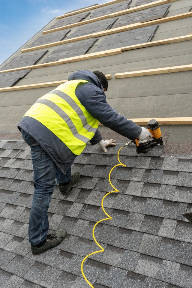 workman installing a new roof using nailgun