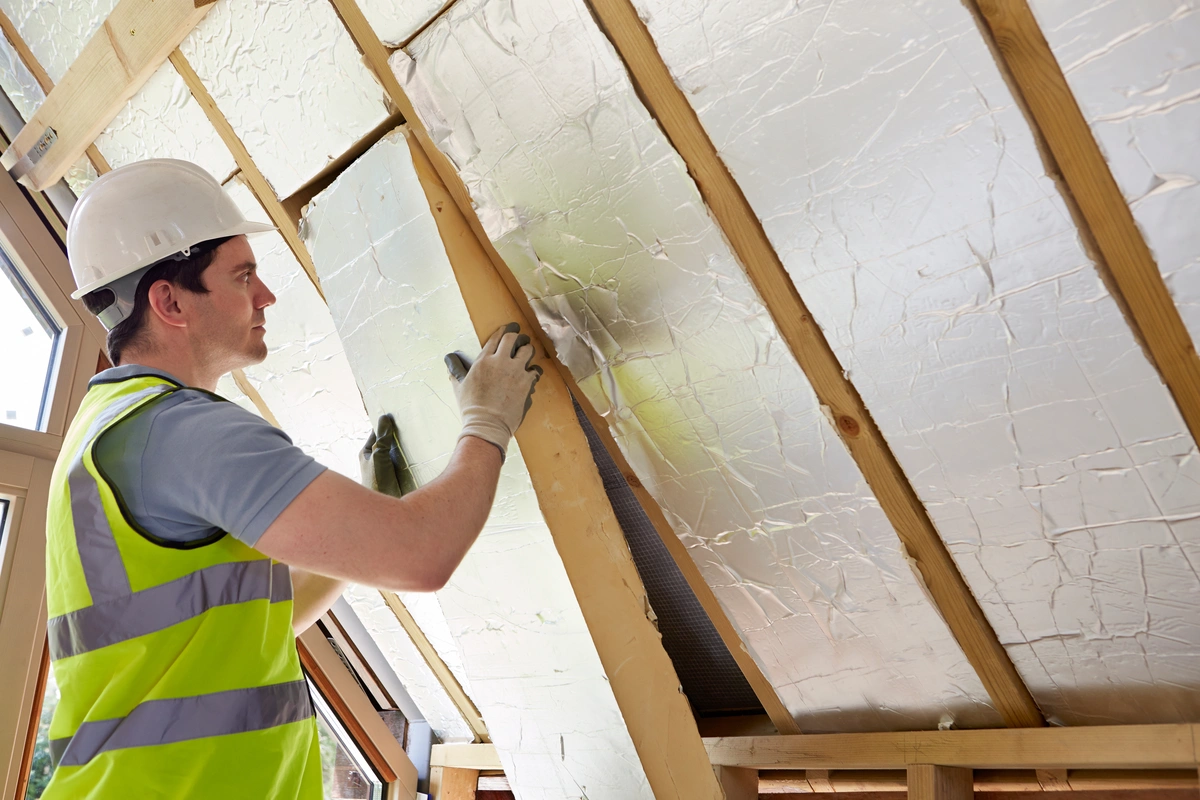 worker in the attic installing insulation