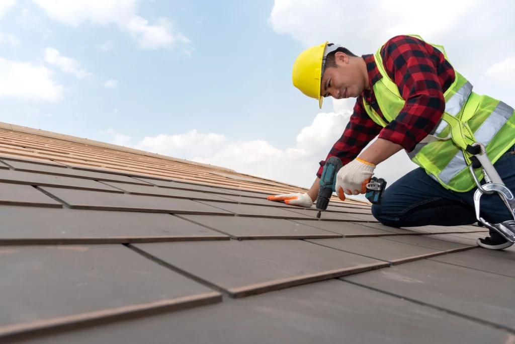Roofer drilling in shingles
