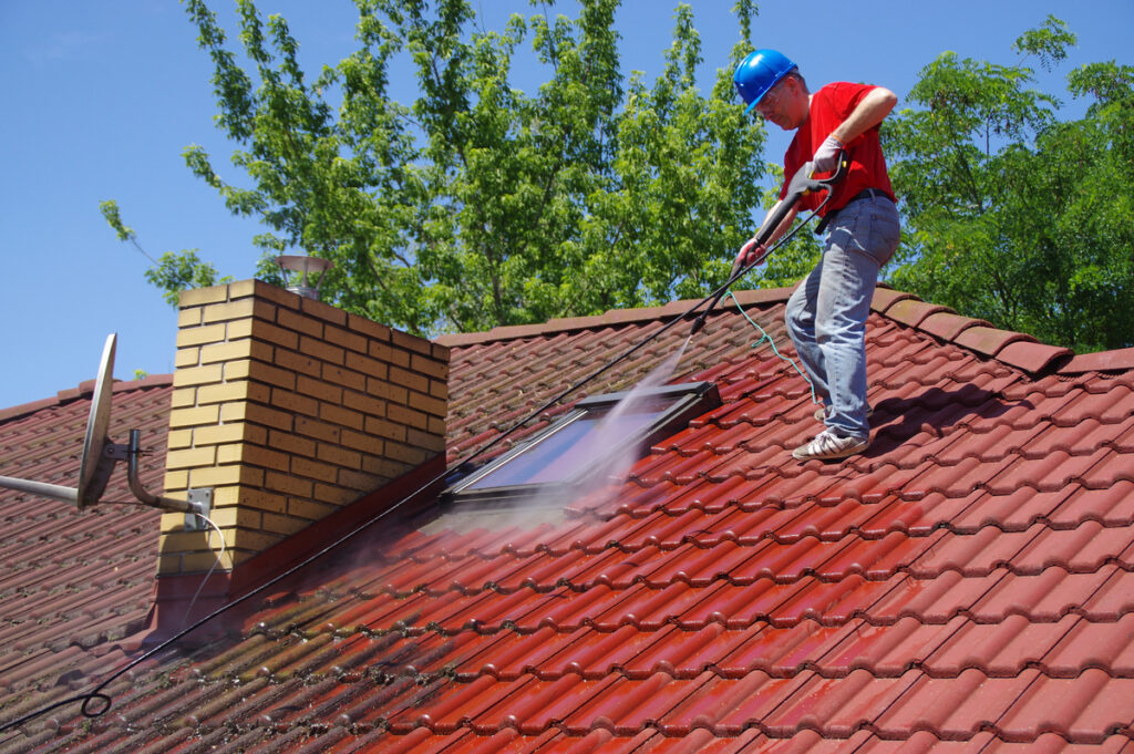 roofing contractor performing roof moss removal on a tile roof