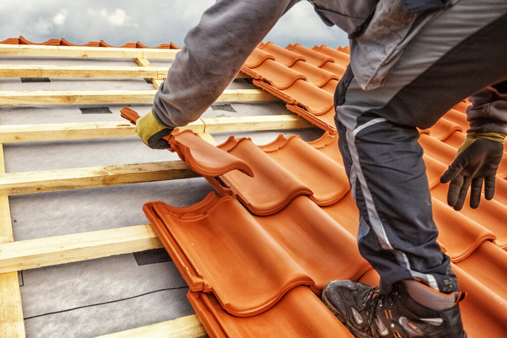 a worker is installing roof tiles