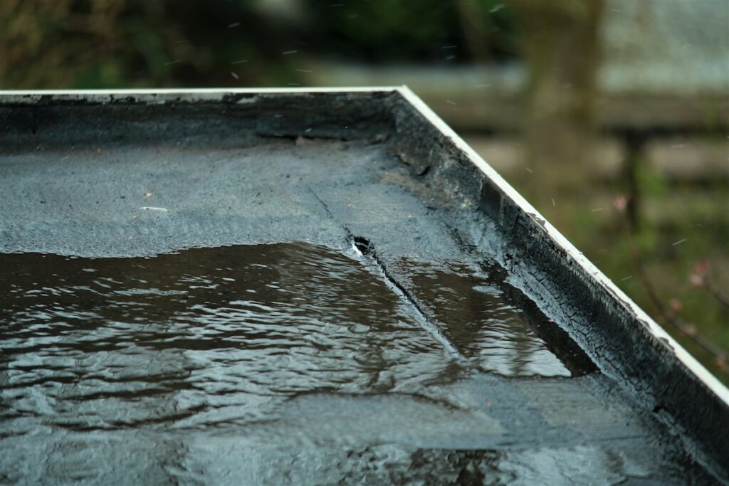Puddle of rain on a black flat roof after hail