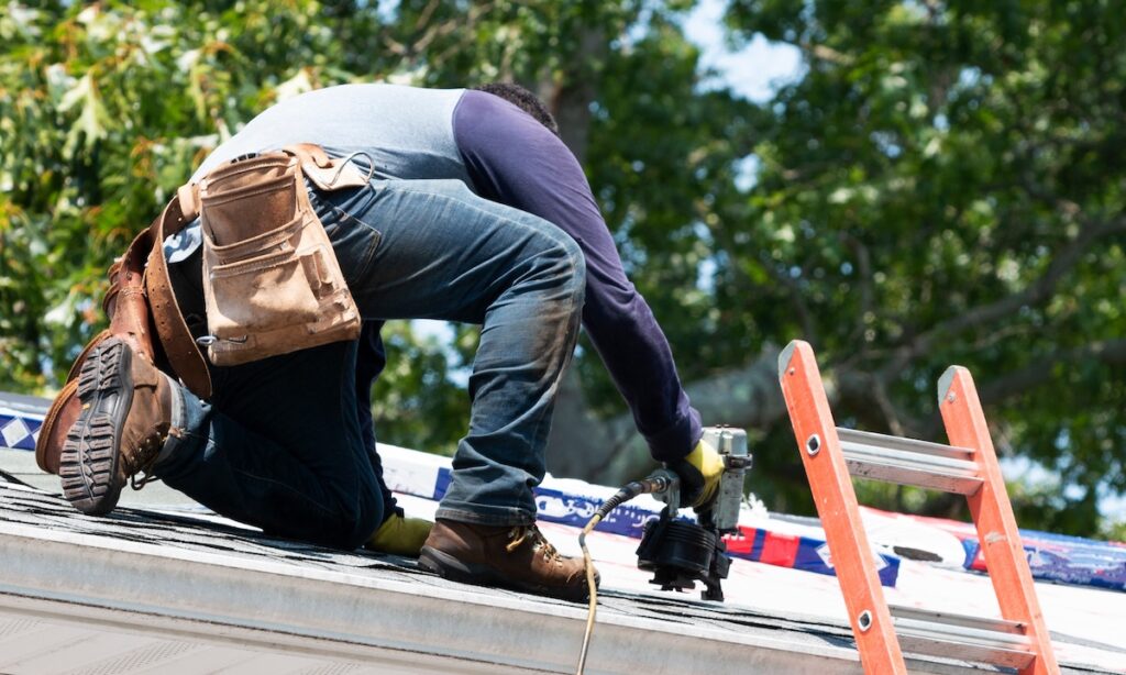 roofer installing shingles with nails 