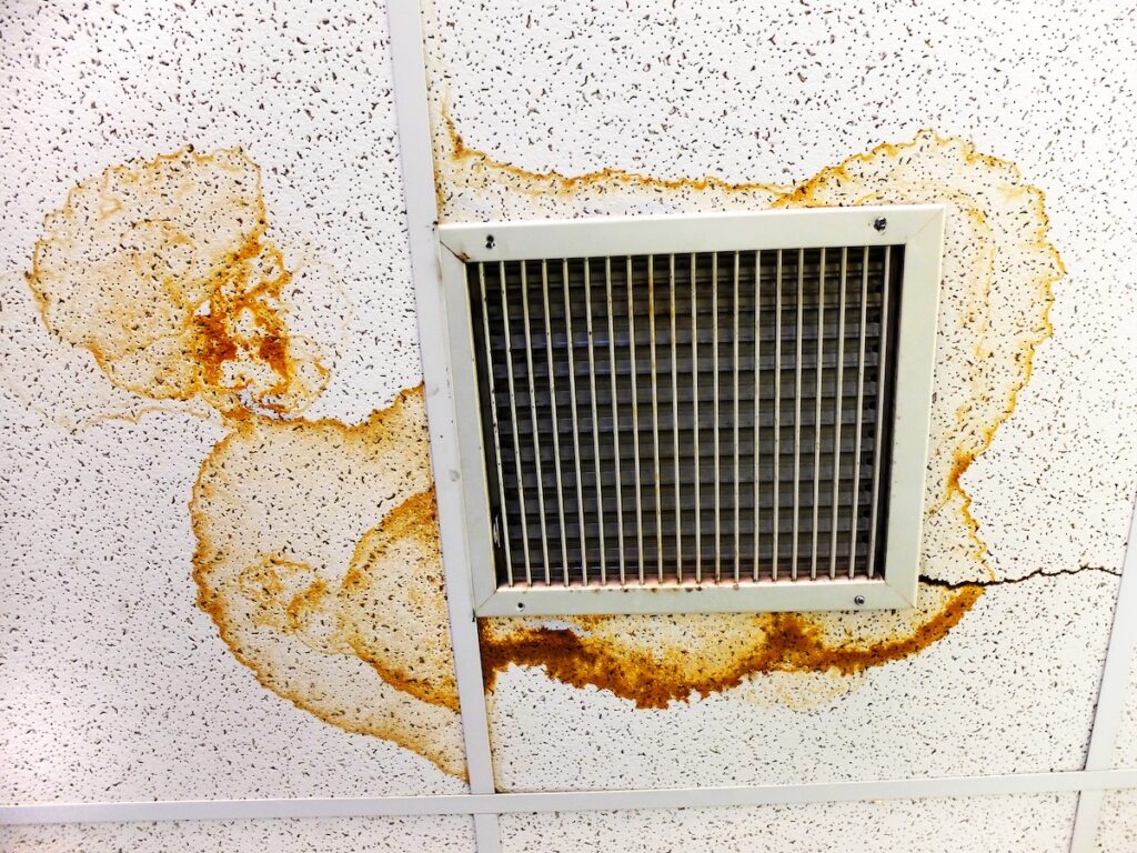 Water damage and stains on ceiling tiles by air vent