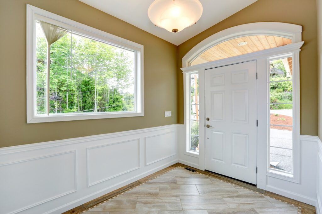Entrance hallway with tile floor and beige wall with white trim.