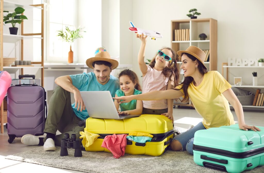 Family of four planning a vacation with their packed suitcases