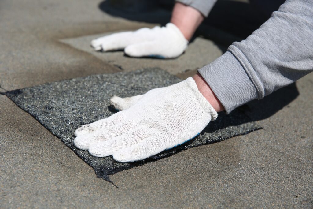 A patch of roofing material being placed over a leaking spot
