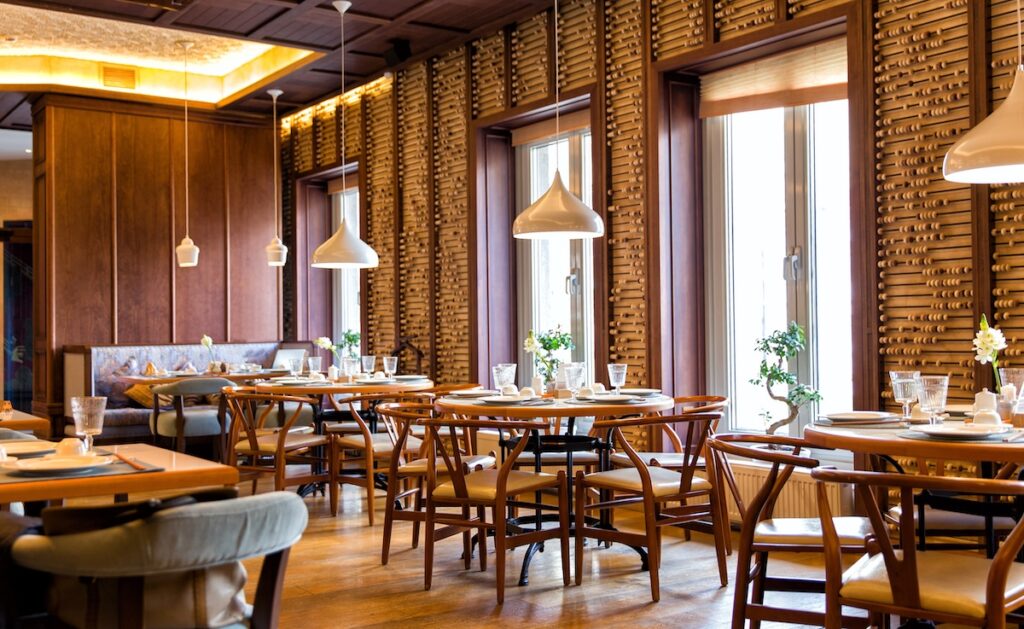 Interior of restaurant, tables and chairs set-up and large windows