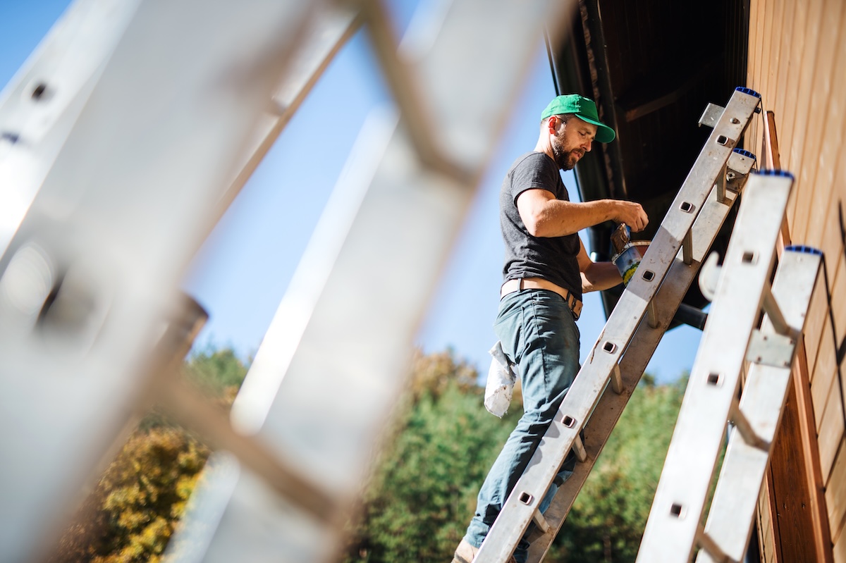 Man working on siding of a wood house