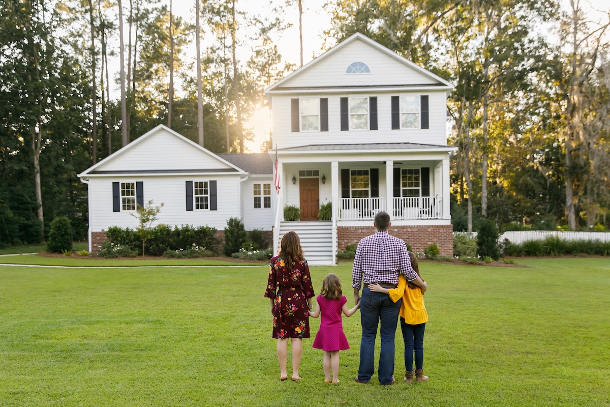 family standing on lawn looking at house