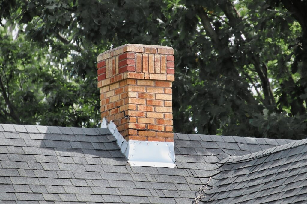 An old chimney on a shingles rooftop with flashing