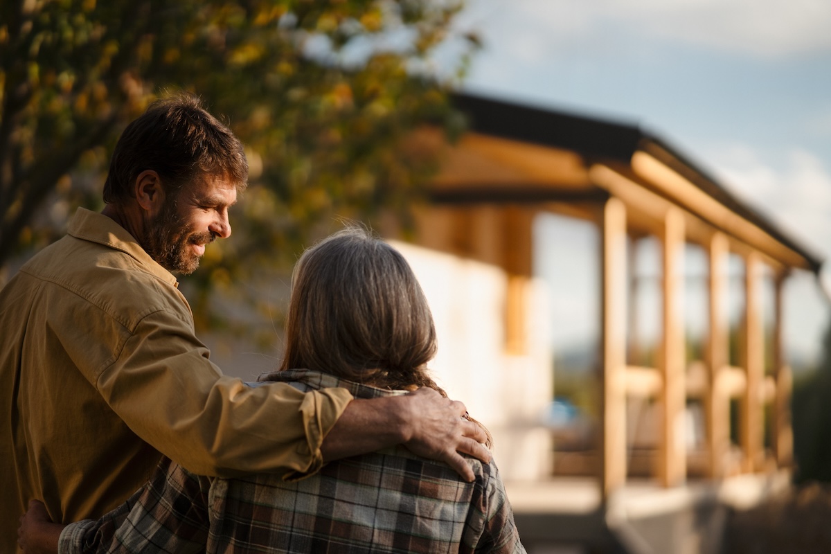 older couple smiling at each other with house blurred in background