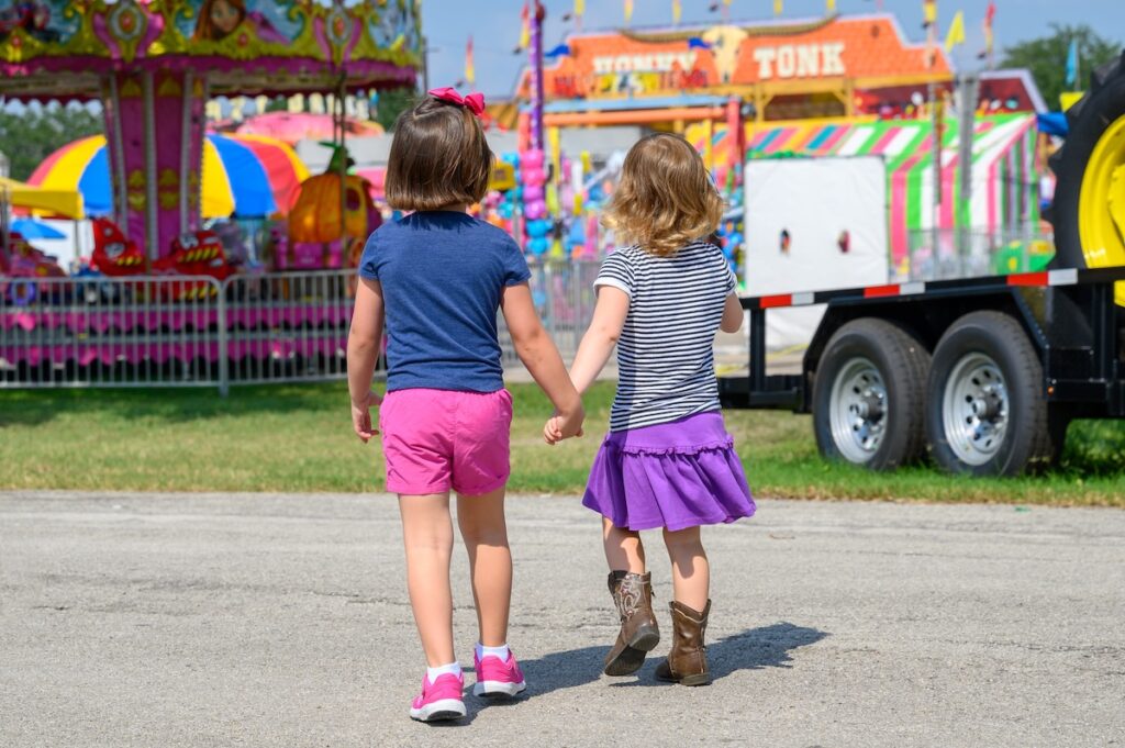 Close up of two young girls walking into county fair.