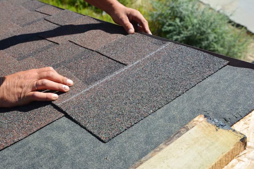 Asphalt Shingles Installation. Roofer Contractor Installing Asphalt Shingles on House Roofing Construction