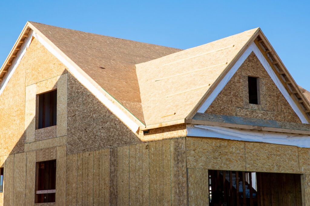 A residential house construction project showing plywood hipe and valley roof
