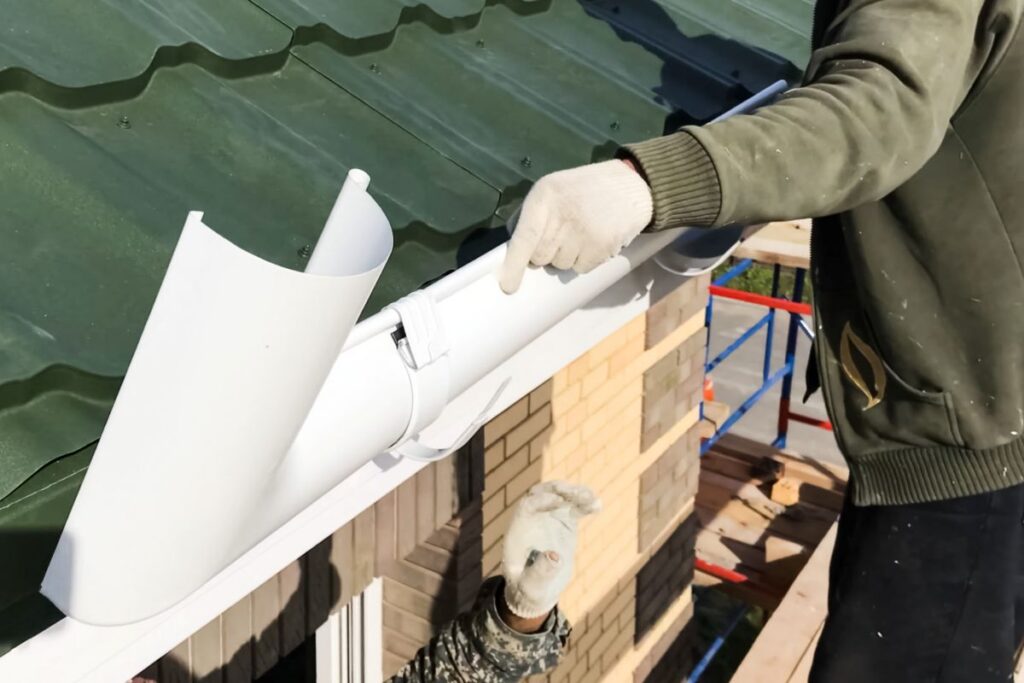 spring gutter cleaning green metallic tiles worker installing gutter system
