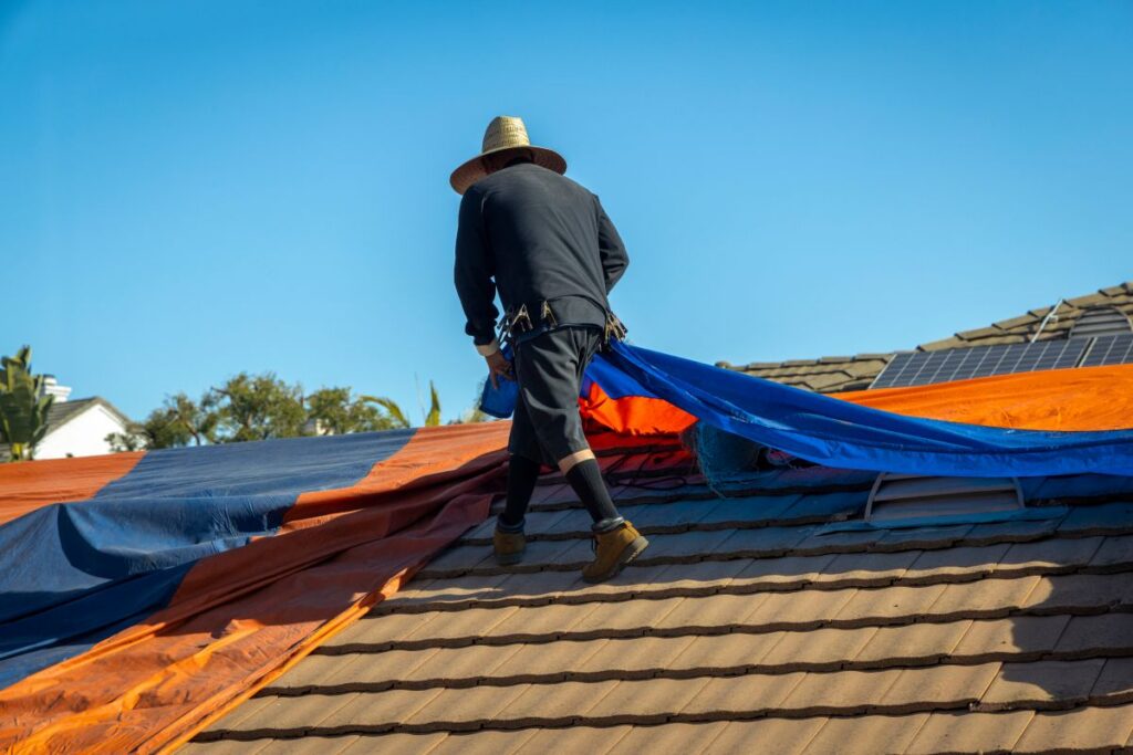 roof tarping worker installing colorful tarp