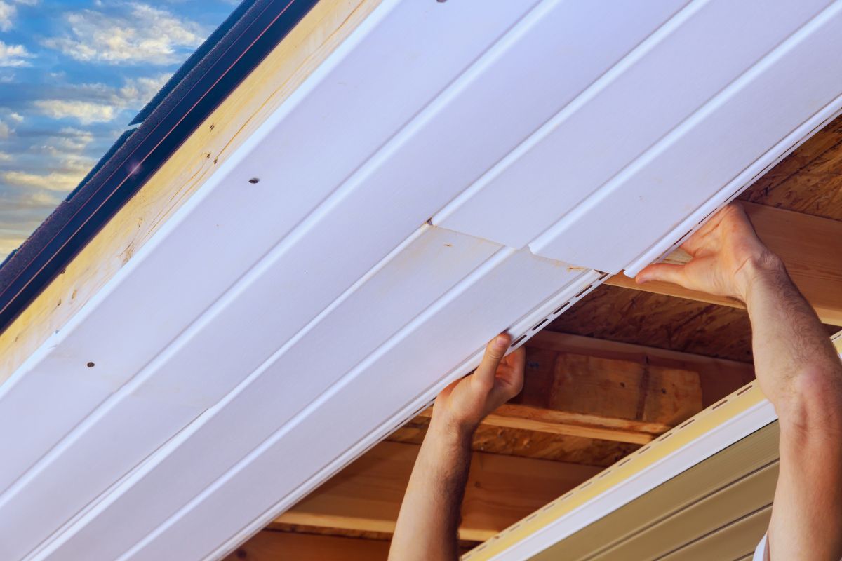 white soffit repair worker using two hands holding roof