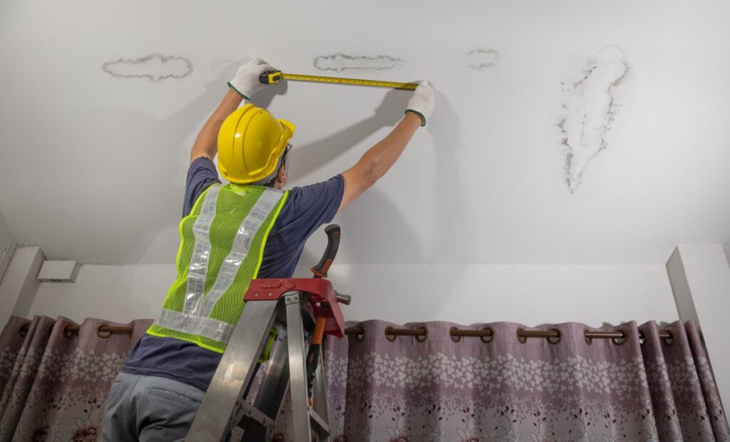 condensation stains on ceiling worker measuring humidity