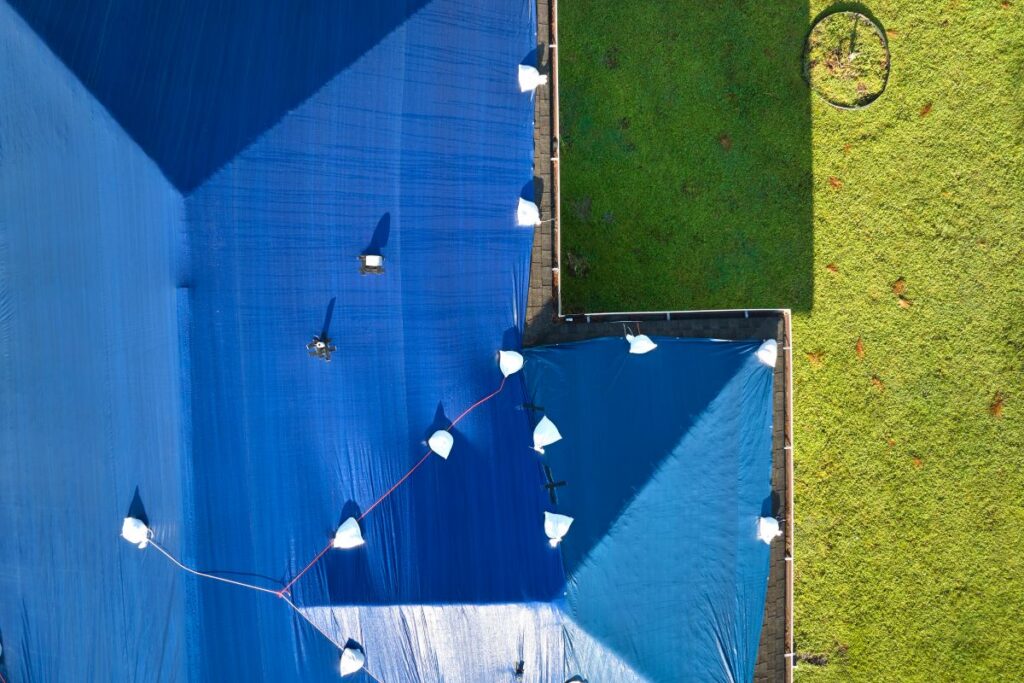 wind damage roof repair blue tarp on top of shingles roof 