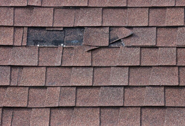 wind damage roof repair brown shingles missing close up dark spots