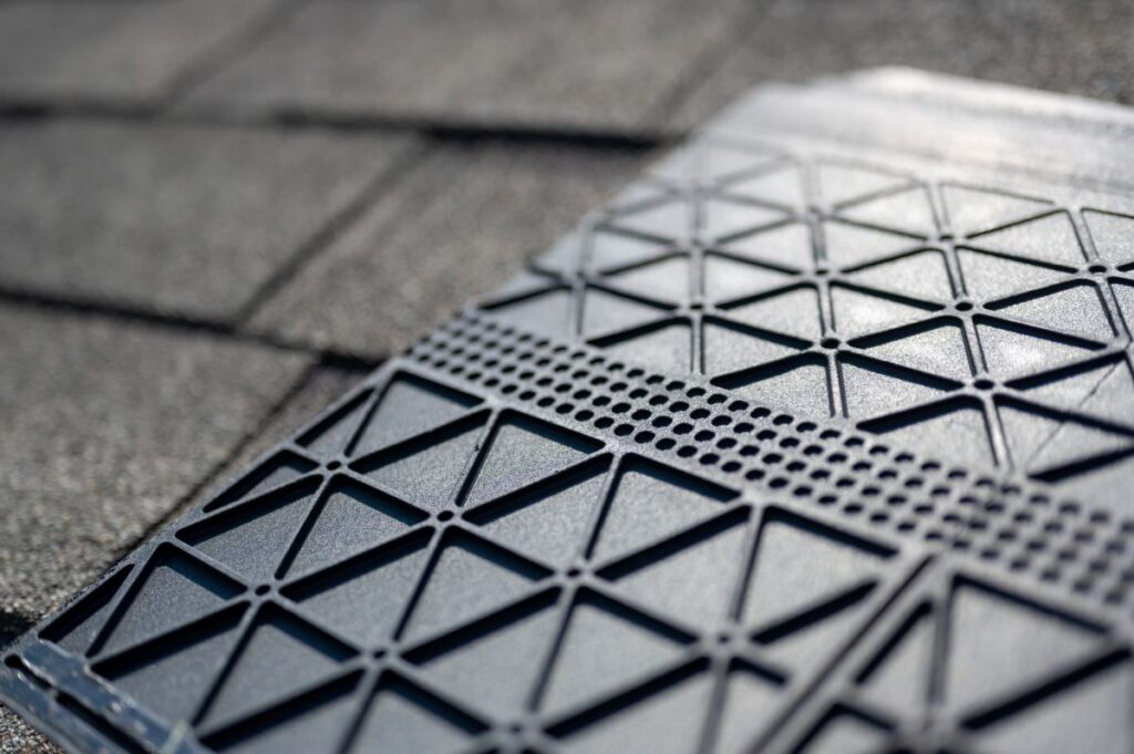 Underside of a synthetic roof shingle that is hail and wind resistant