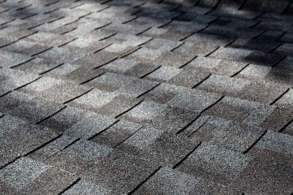 close-up of an asphalt shingle roof at an angle with dappled sunlight