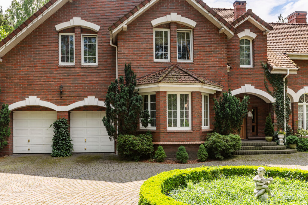 bay window installation Real photo of a brick house with a bay window, garages and round garden in front of the entrance