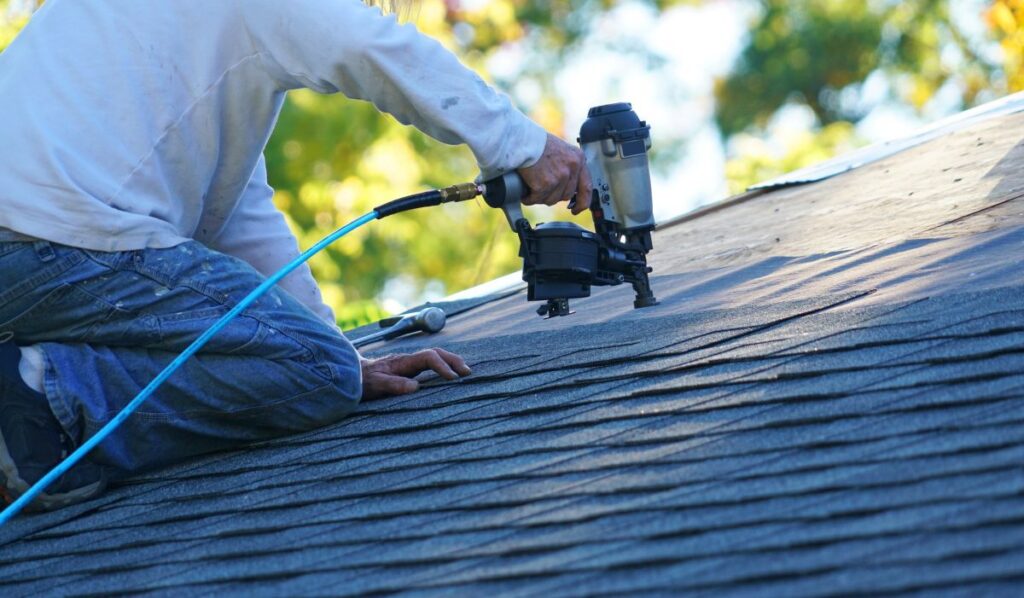 roofer repairing asphalt roof with nail gun